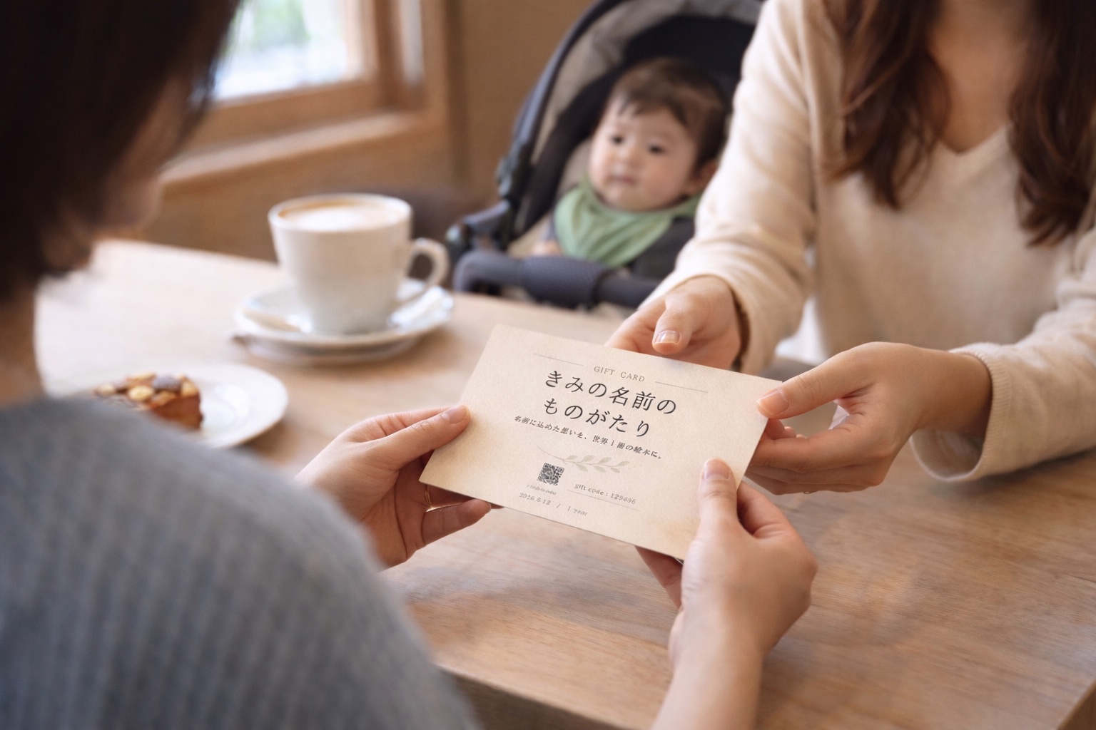赤ちゃんを連れたご家族へ、カフェのテーブル越しに絵本のギフトカードを手渡す様子