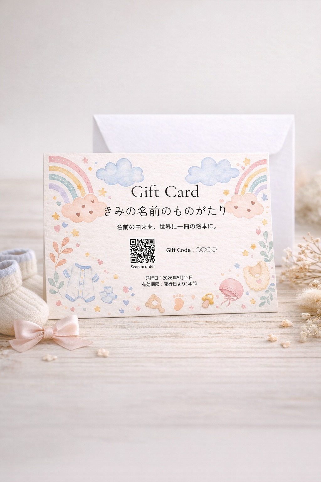 ベビー用品と花を添え、封筒と一緒に飾った出産祝い用の郵送ギフトカード